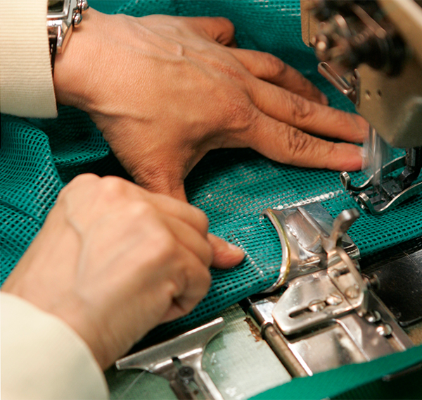 associate using sewing machine to attach parts of a jacket