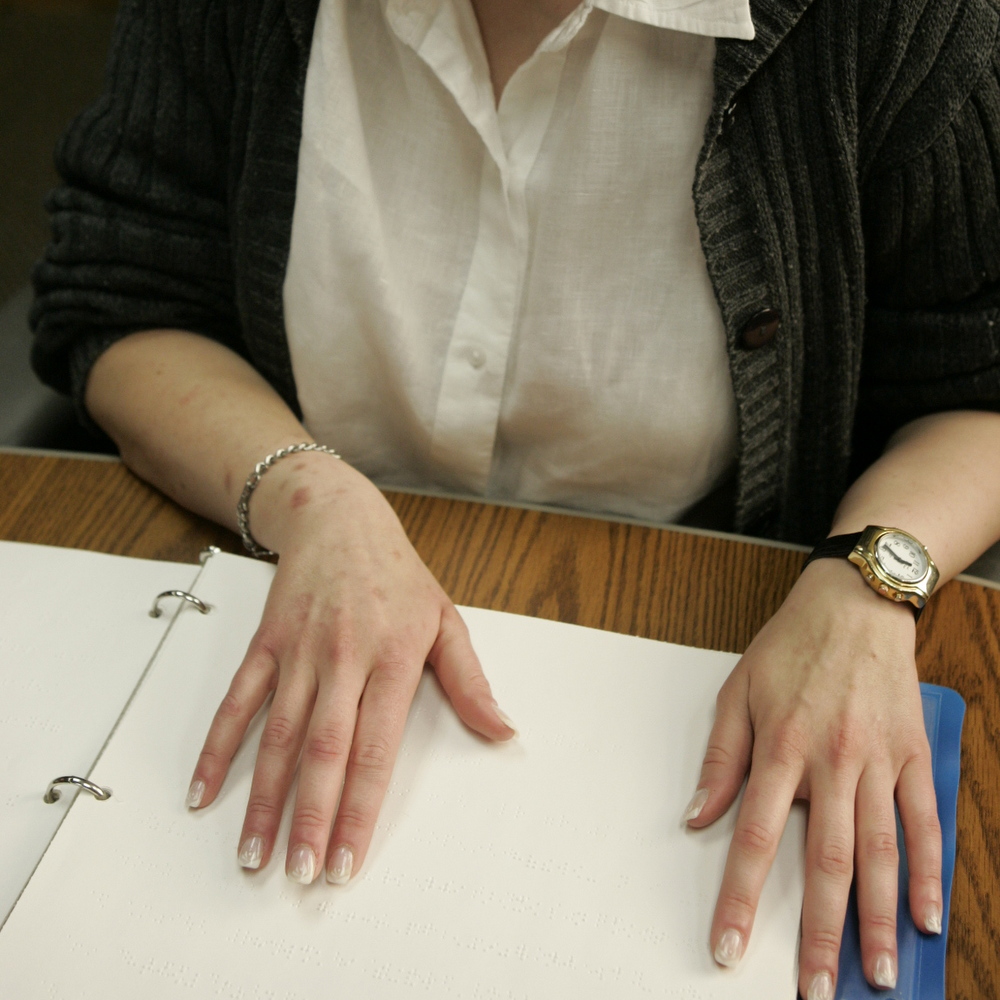 close up on woman's hands reading Braille